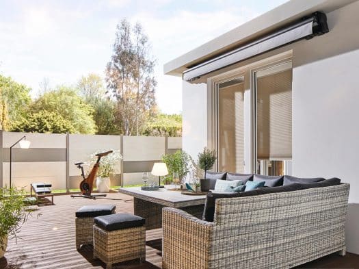 Gelenkarmmarkise an Hauswand über Terrasse mit Rattan-Lounge